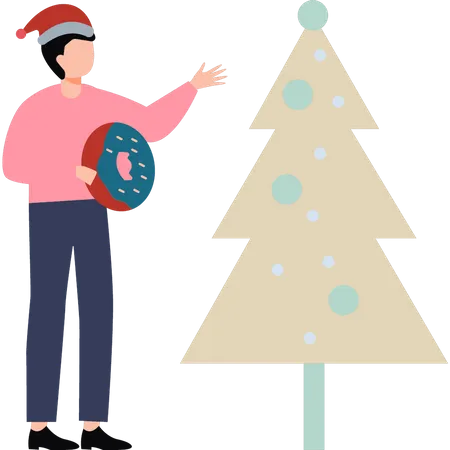 A boy with a donut stands by a Christmas tree  Illustration