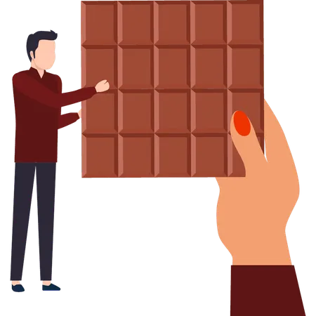 Le garçon regarde la barre de chocolat  Illustration