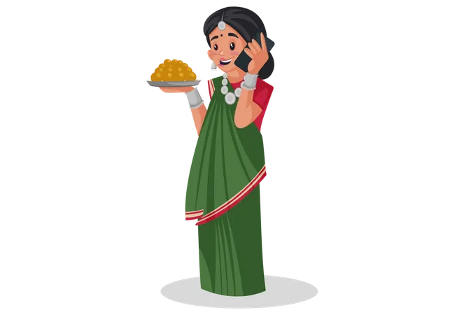 Mujer gujarati sostiene un plato de dulces en la mano y habla por teléfono móvil  Ilustración