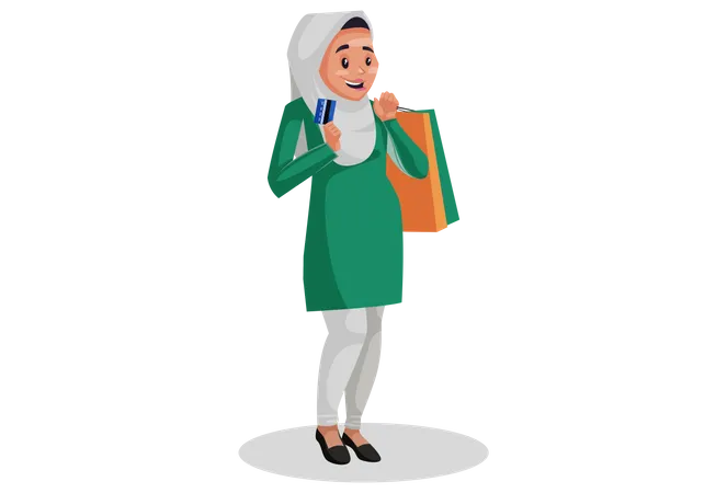 Muslim woman is holding shopping bags and ATM card in hands for online shopping payment  Illustration